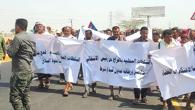 مشاركون يحملون شعارات تندد بالاعتقالات