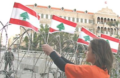 فتاة لبنانية تضع الاعلام على السور وسط بيروت