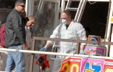 خبير في مكتب البحث الجنائي الاسرائيلي ينقل احد الآشلاء من مكان الحادث