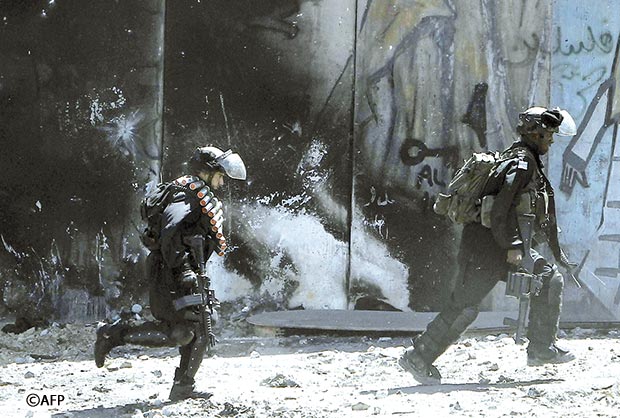 جنود إسرائيليون يجرون أمام لوحة ضخمة للرئيس الفلسطيني الراحل ياسر عرفات أمس