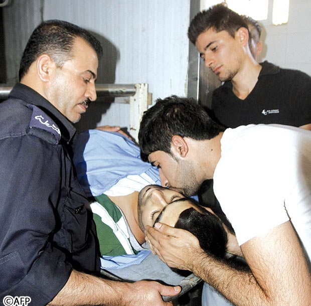 شاب فلسطيني يقبل شقيقه الذي استشهد في القصف الإسرائيلي أمس