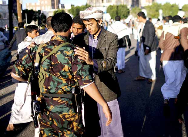 حوثي يقوم بتفتيش رجل امن بصنعاء