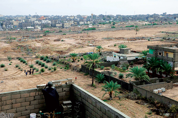 جندي مصري على سقف أحد المباني يقوم بمراقبة الحدود وتظهر مدينة رفح الفلسطينية بالجهة المقابلة جندي مصري على سقف أحد المباني يقوم بمراقبة الحدود وتظهر مدينة رفح الفلسطينية بالجهة المقابلة